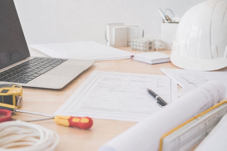 Cuffie senza fili e mouse appoggiati sulla scrivania davanti a un computer acceso